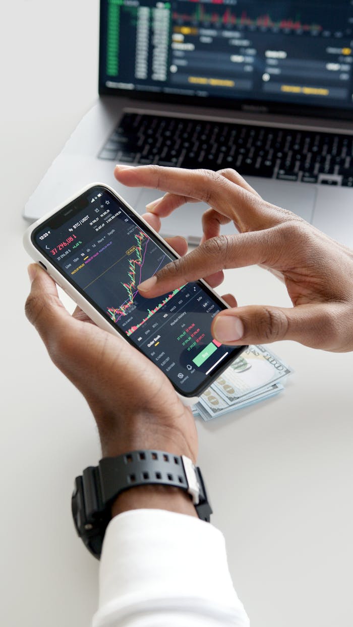 Mastering the First Impression: Your intriguing post title goes here Hands using smartphone trading app with charts, dollar bills in background.