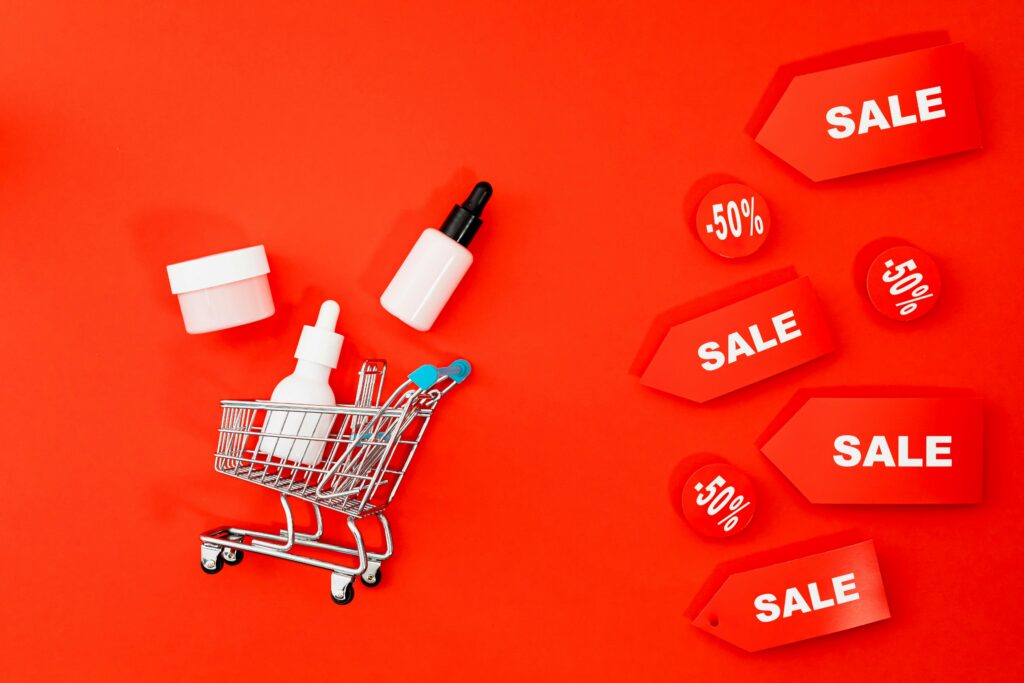 Skincare items in mini cart with sale tags on red background. Perfect for Black Friday ads.
